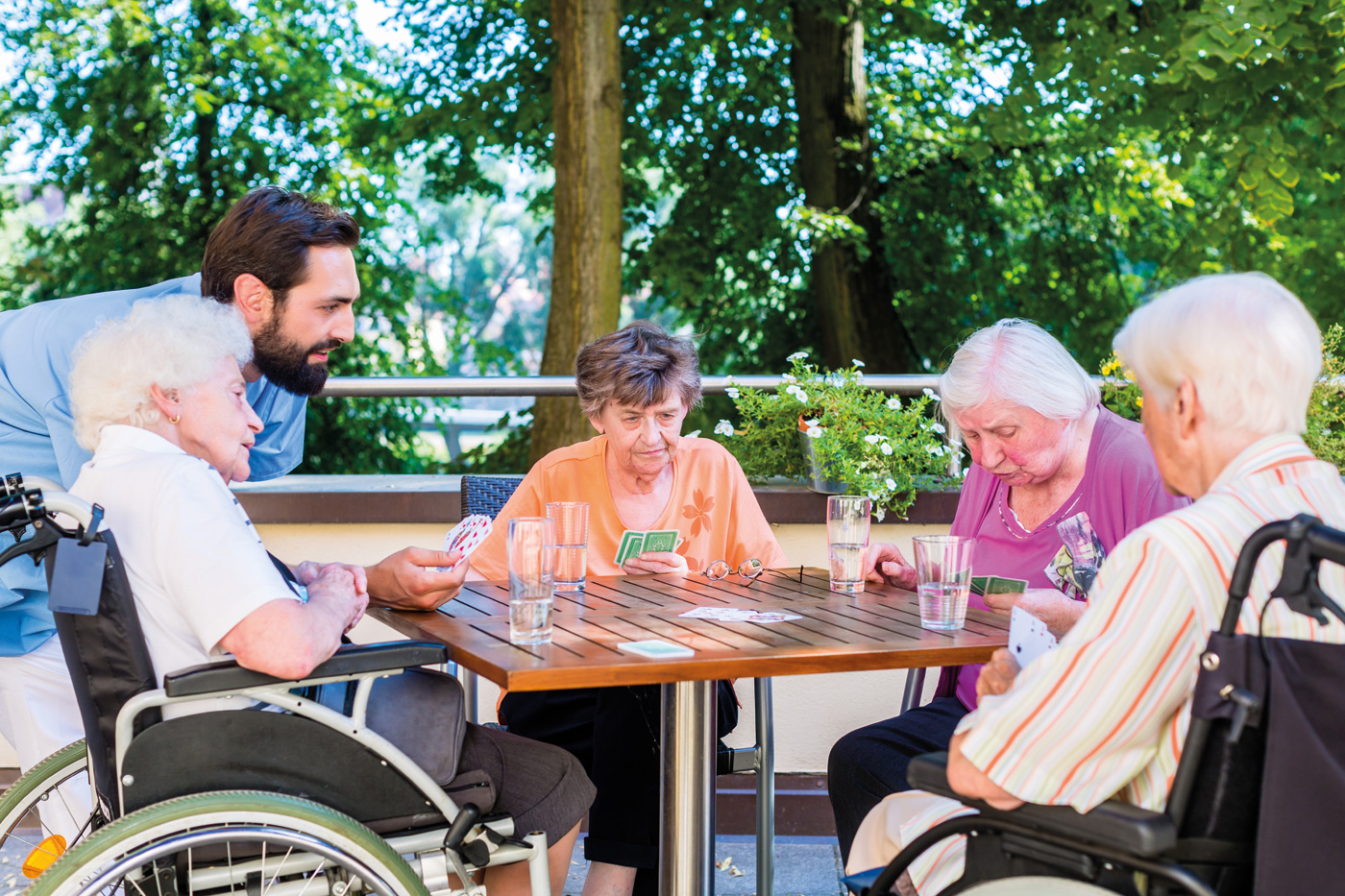 Eine Gruppe von älteren Damen spielt Karten, ein junger Mann schaut zu