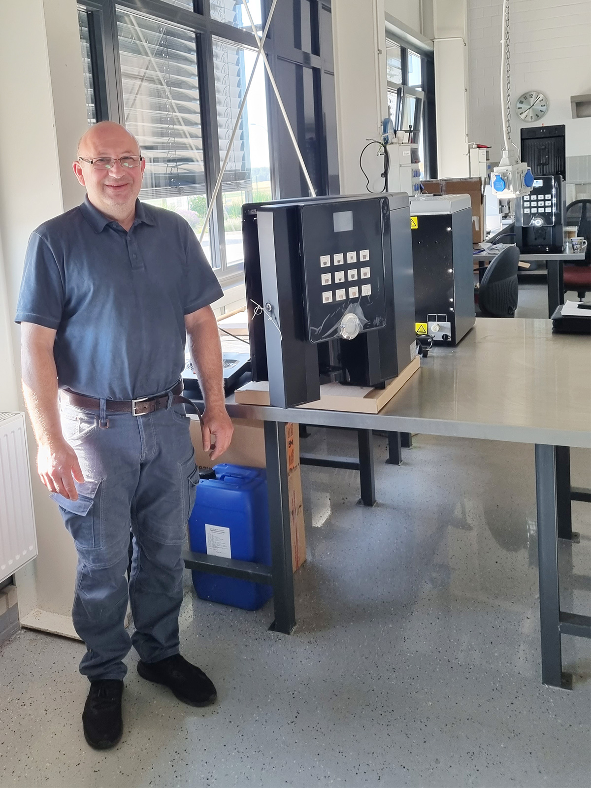 Ein Mann steht vor einem geöffneten Kaffeeautomaten, um diesen technisch zu warten