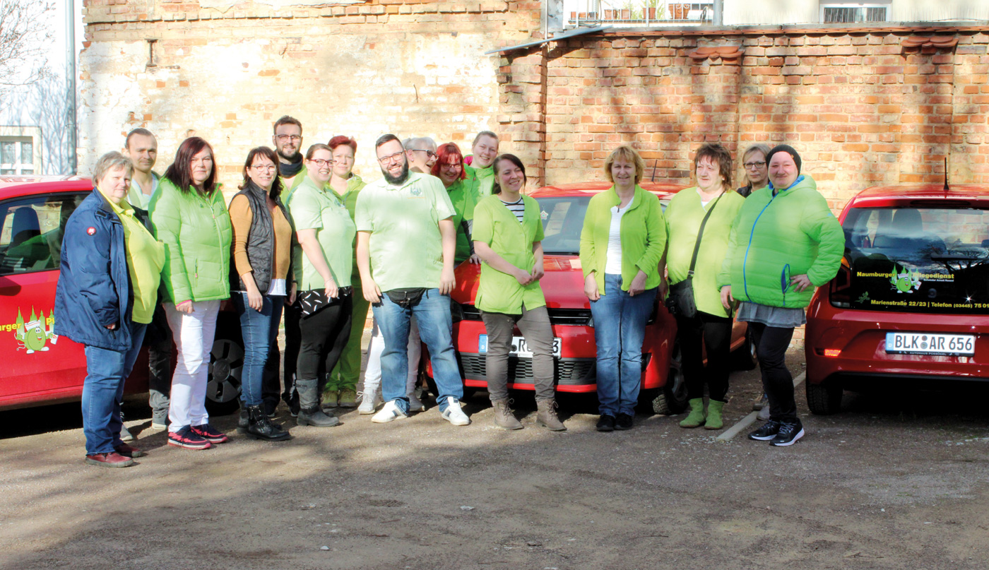 Eine Gruppe von Menschen stehen vor 3 Autos