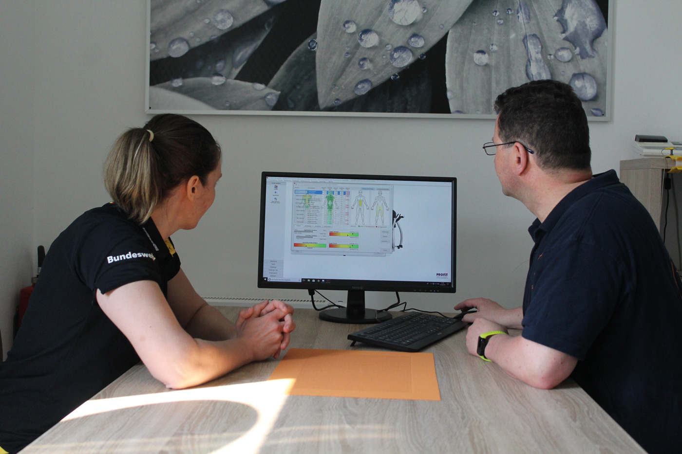 Ein Mann und eine Frau haben dem Fotograft den Rücken zugewandt. Sie schauen auf einen Bildschirm.