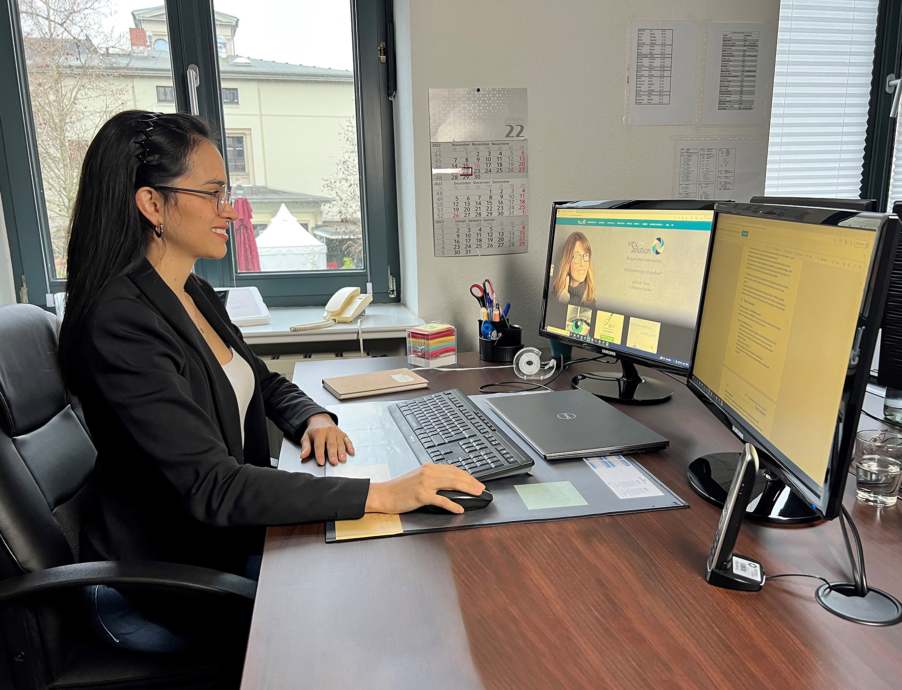 Eine junge Frau sitzt sehr gut gelaunt an einem Computerarbeitsplatz