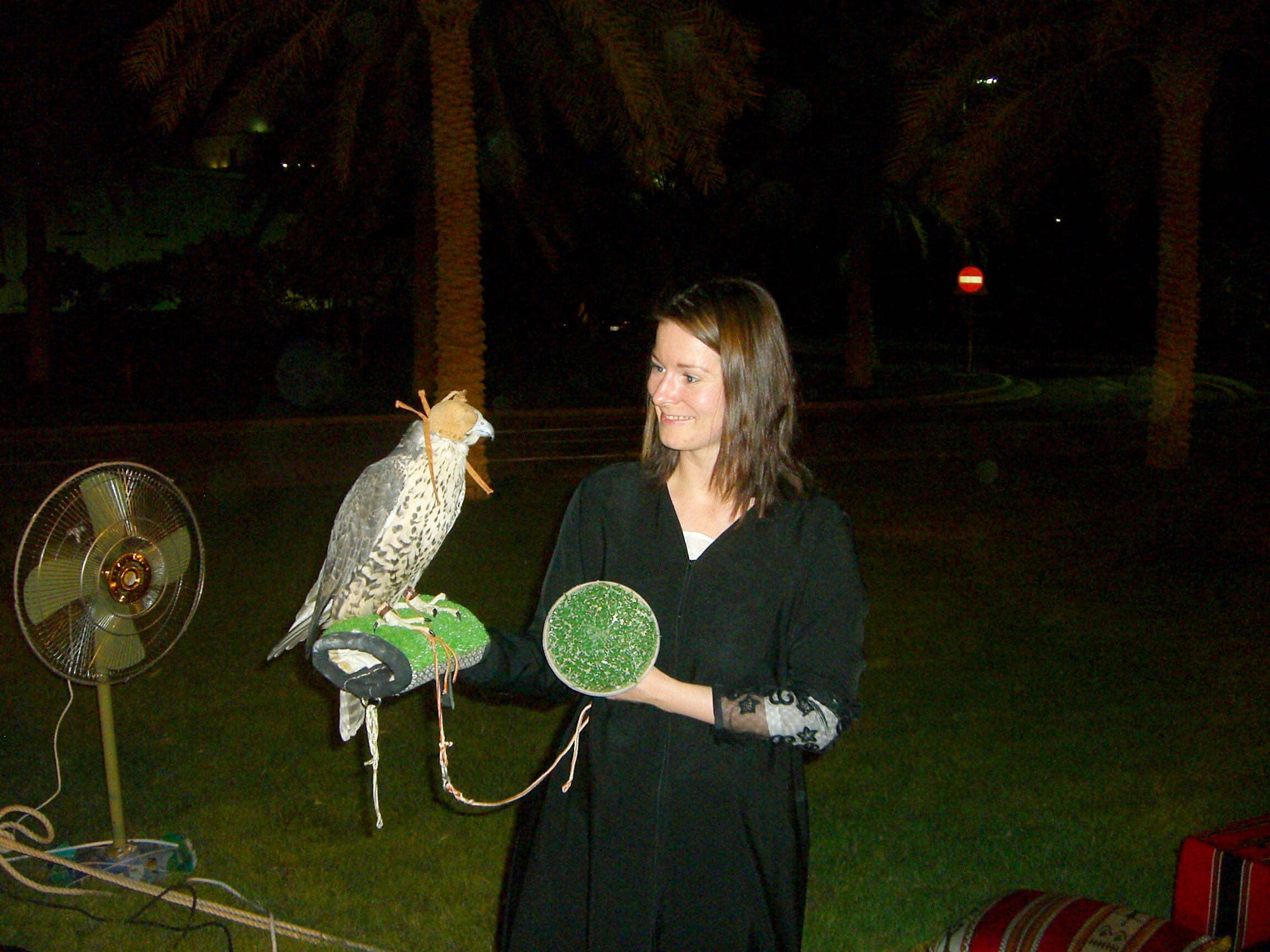 Eine Frau hat einen Falken auf dem Arm.