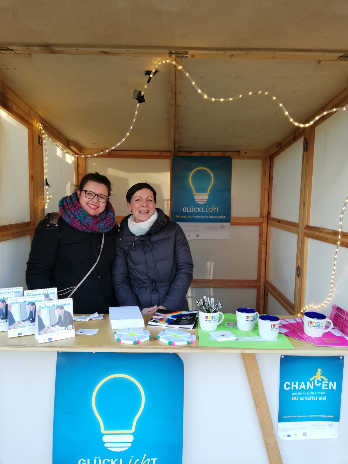 Zwei Frauen stehen gut gelaunt in einer Holzhütte