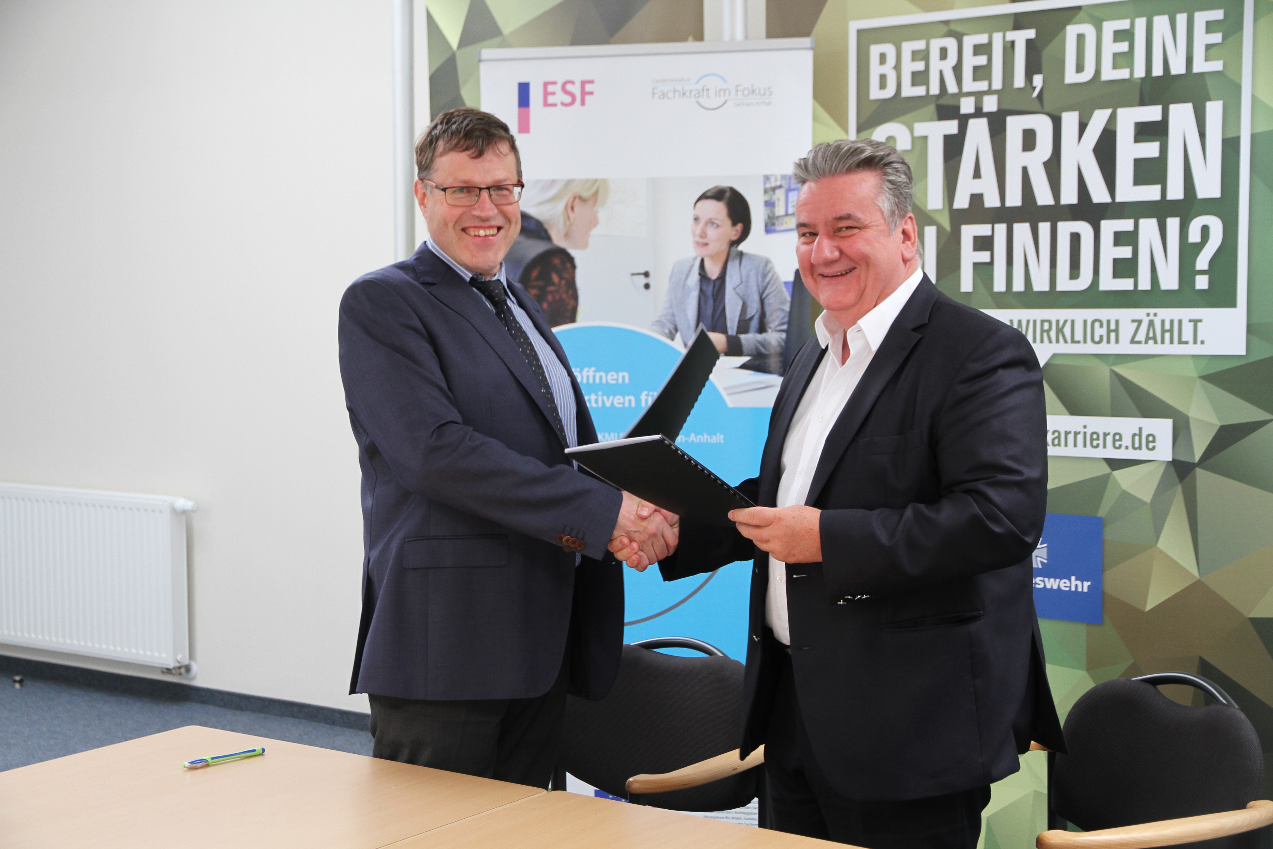 Zwei Männer schütteln sich die Hände nachdem sie einen Kooperationsvertrag unterschrieben haben.