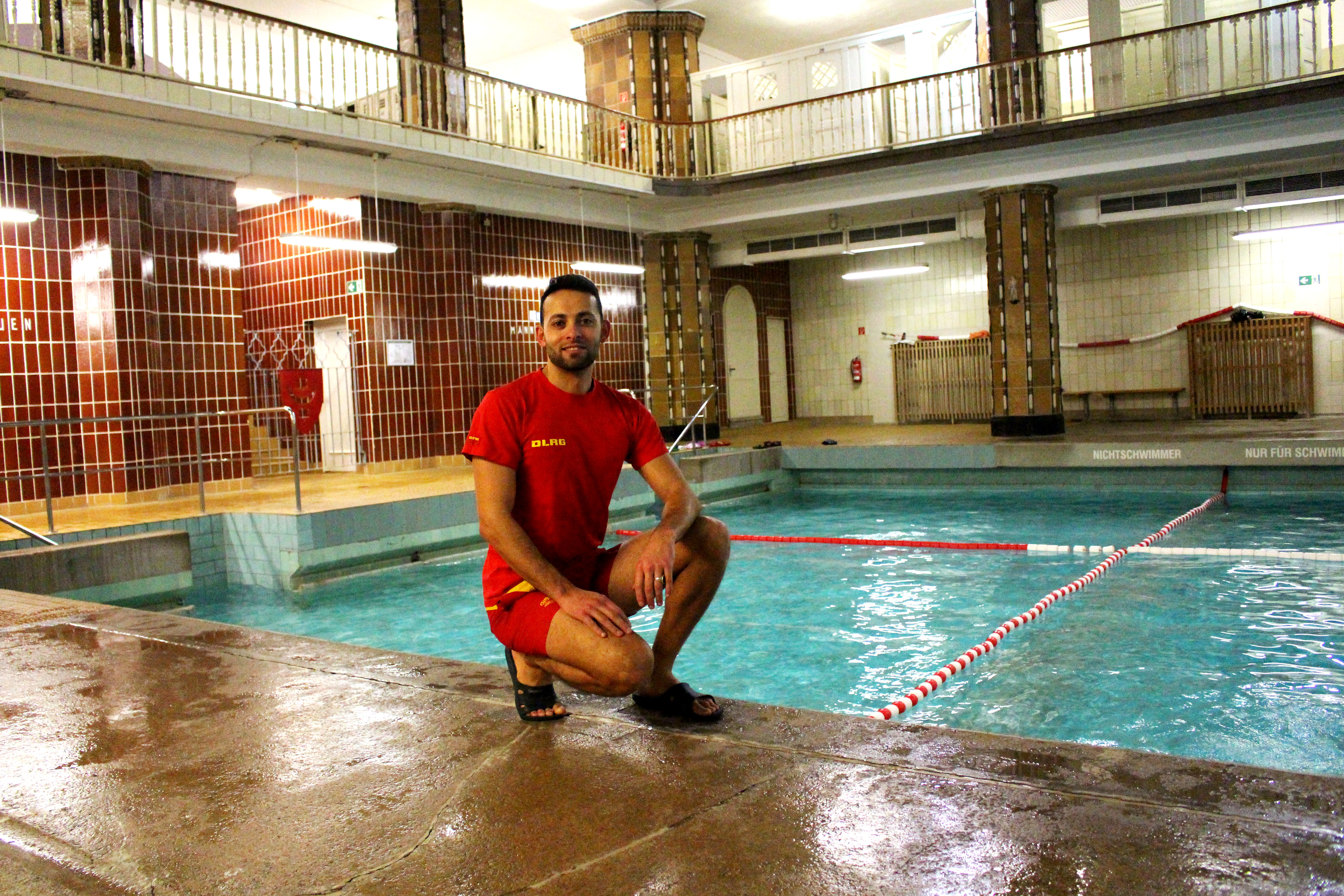 Ein Mann am Beckenrand eines Schwimmbades