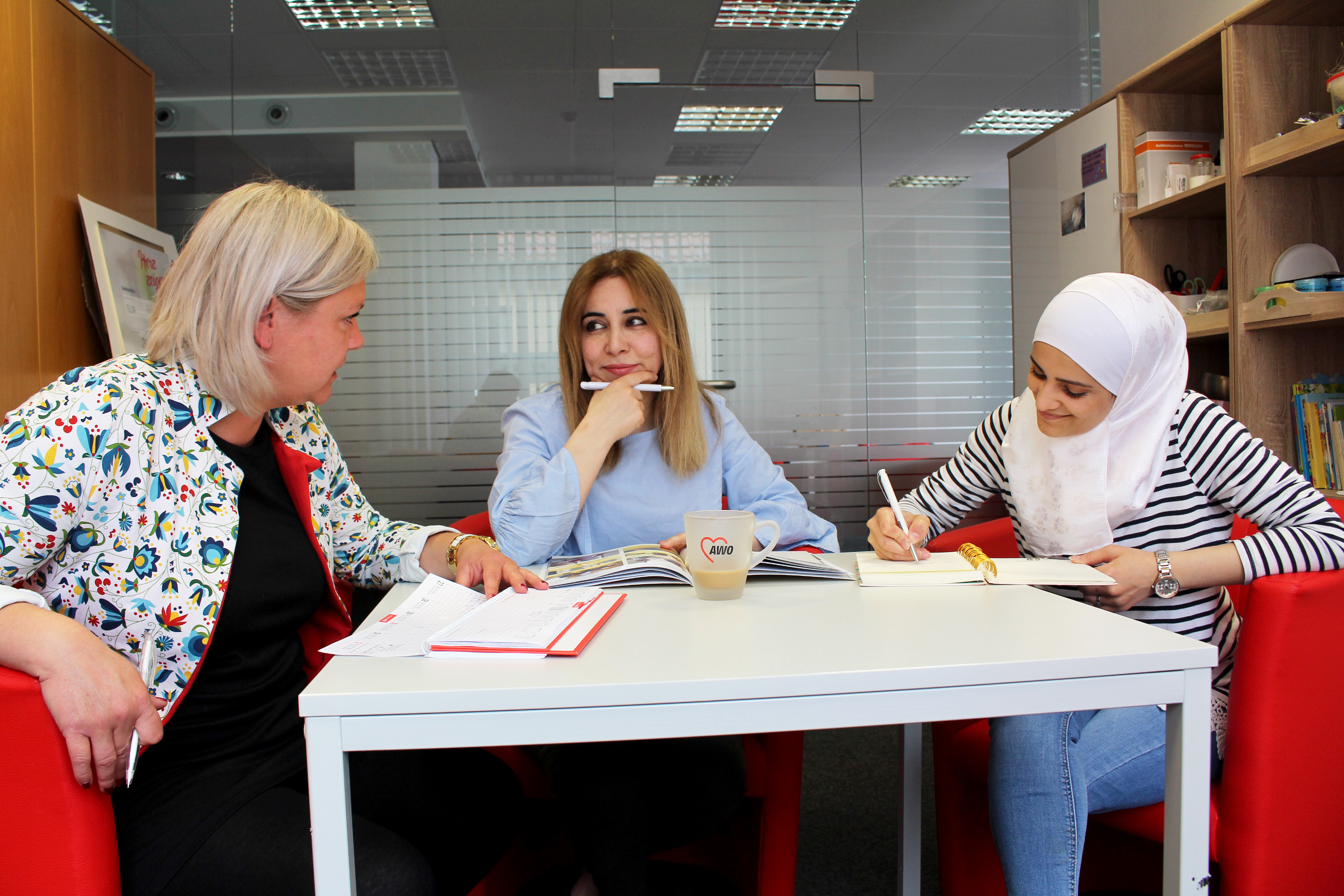 Drei Frauen sitzen an einem Tisch und reden miteinander.