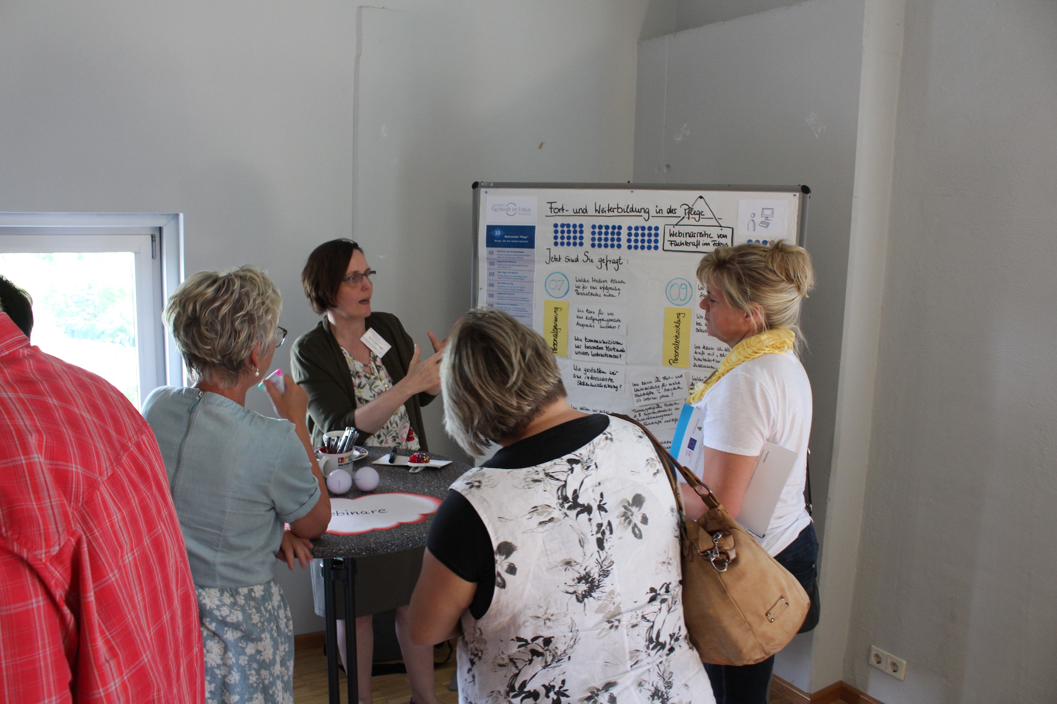 Frauen stehen vor einer Informationstafel und tauschen sich aus