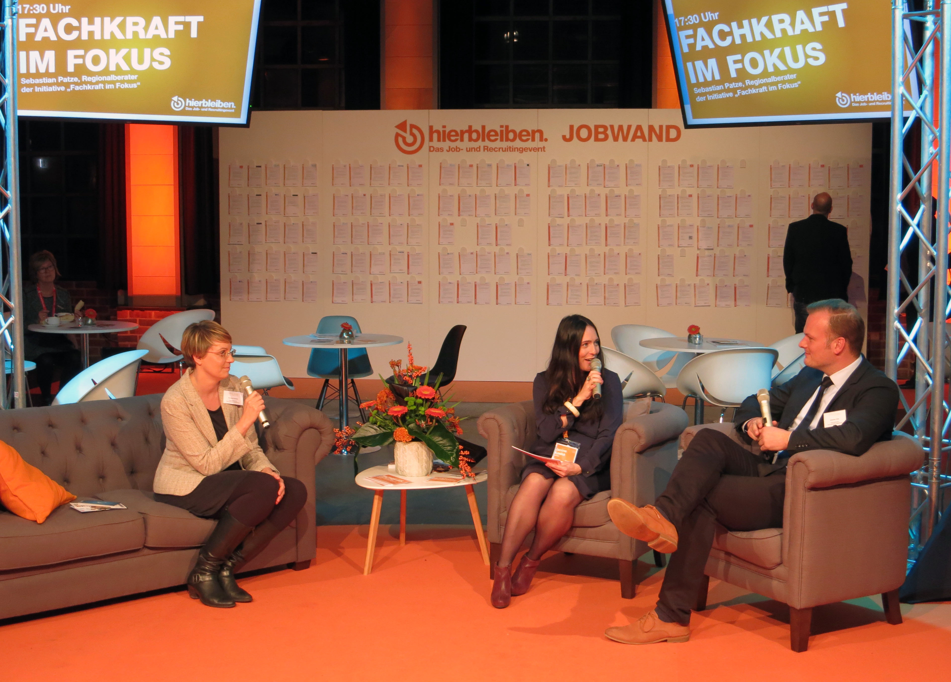 Zwei Frauen und ein Mann unterhalten sich auf einem Sofa