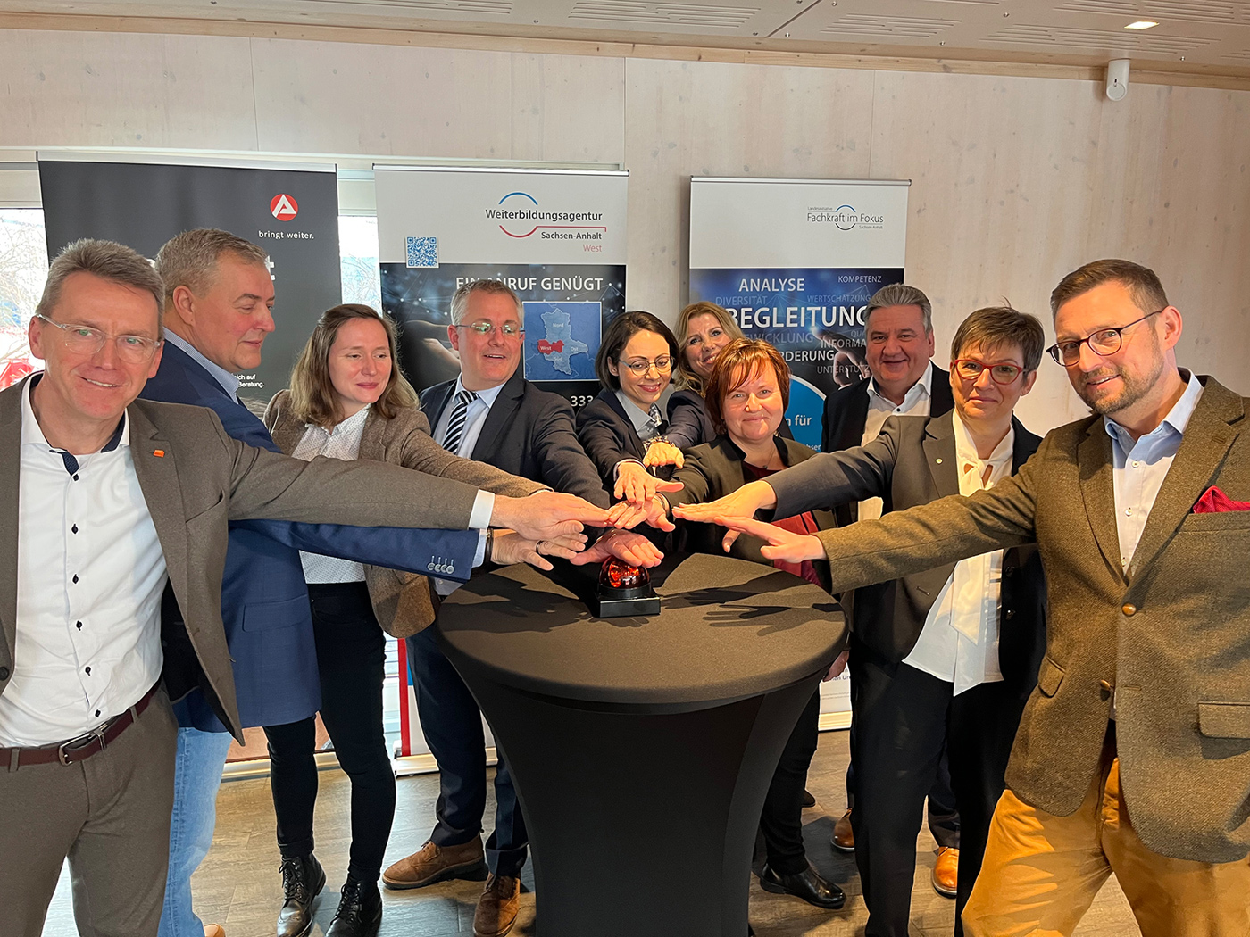 Eine Gruppe von Menschen steht drückt gemeinsam einen Buzzer