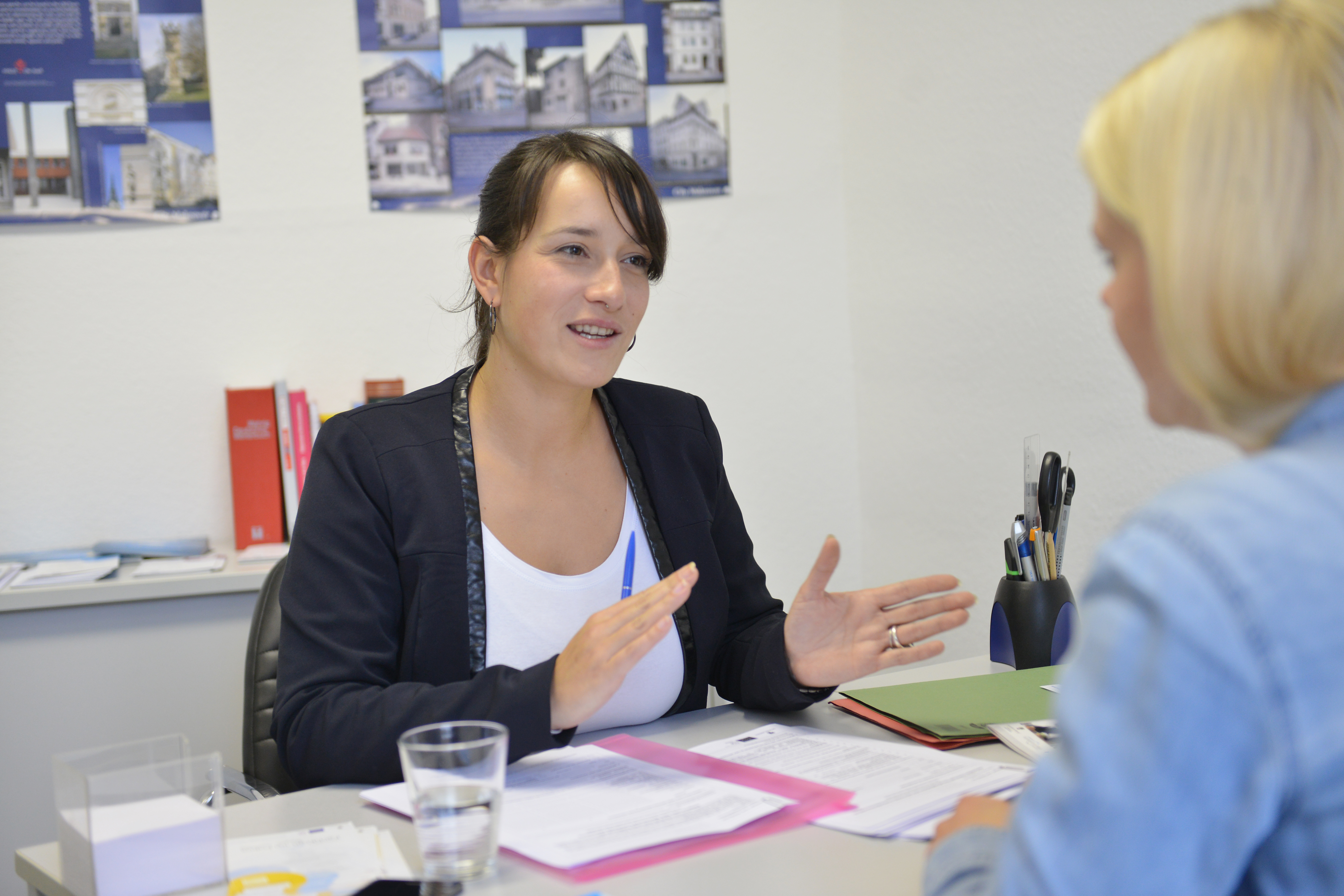 Eine dunkelhaarige Frau berät eine blonde Frau an einem Tisch