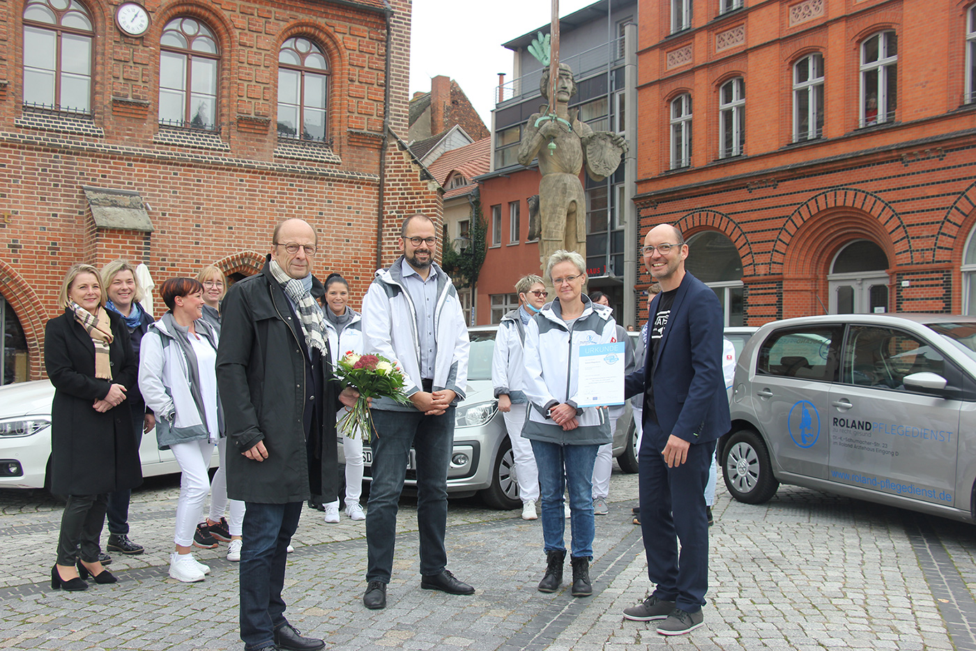 Geschäftsleiter und Leiterin Pflegedienst bekommen Urkunde und Blumen überreicht